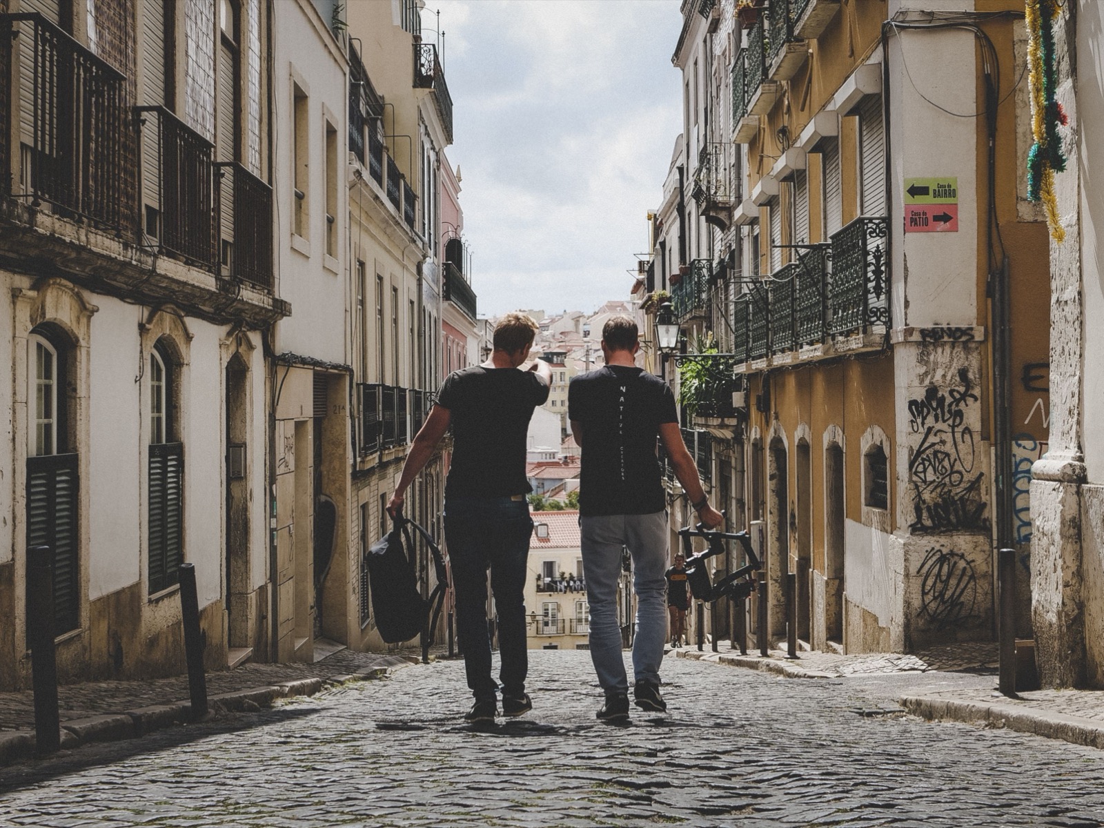 Two people walk down a Lisbon street with what they have just bought.